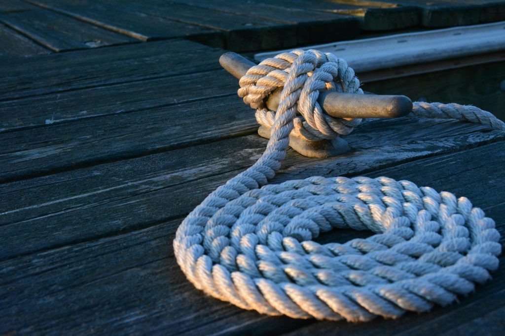 pexels-photo-275637-275637 Close-up of a sturdy nautical knot on a weathered wooden dock at sunset.